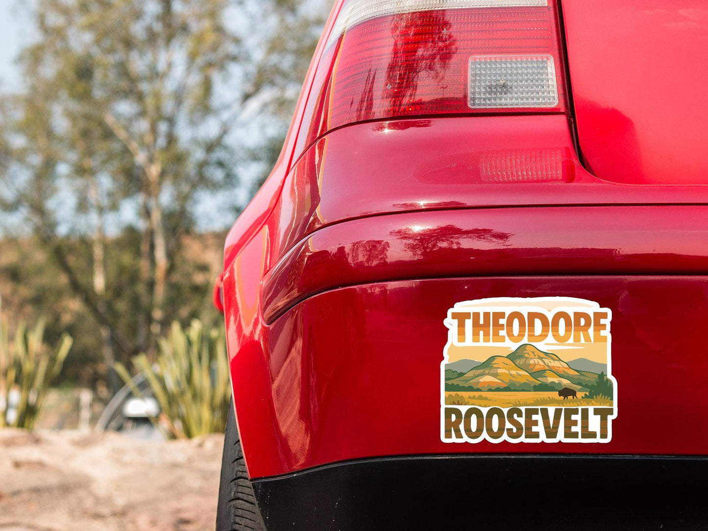 the rear end of a red car with a sticker on the back window that says "THEODORE ROOSEVELT".