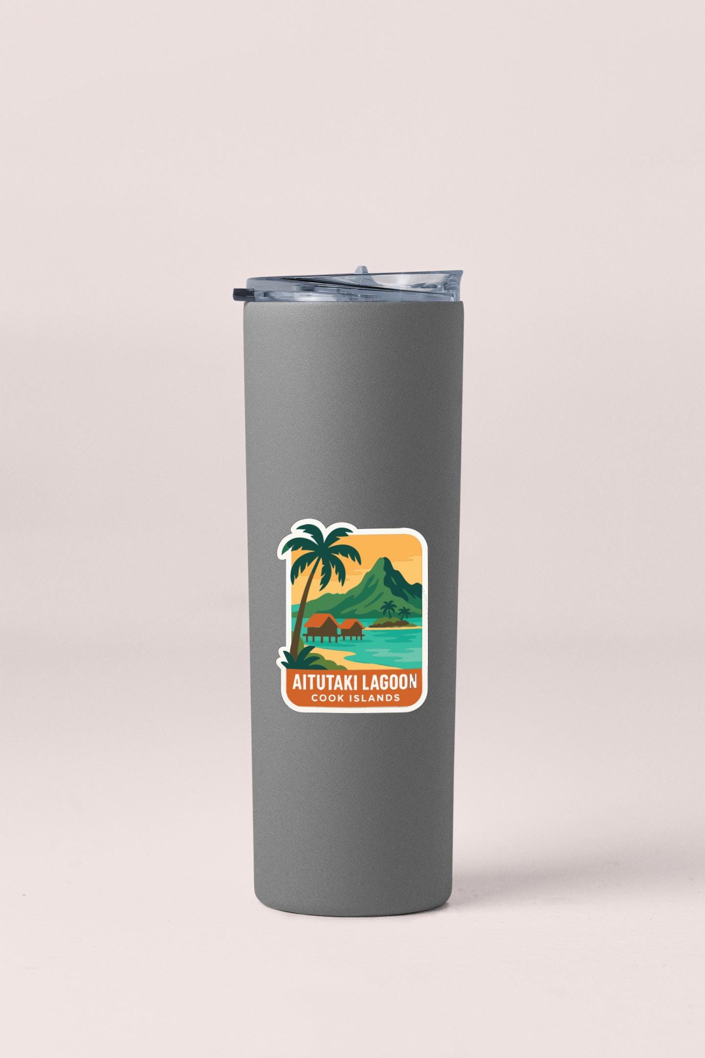 A gray insulated tumbler with a sticker depicting a tropical island landscape.