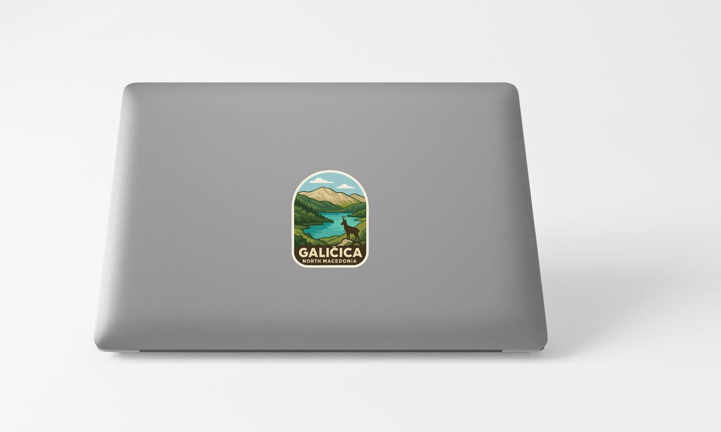A sticker with a scenic landscape of mountains and a lake is affixed to the back of a laptop computer.