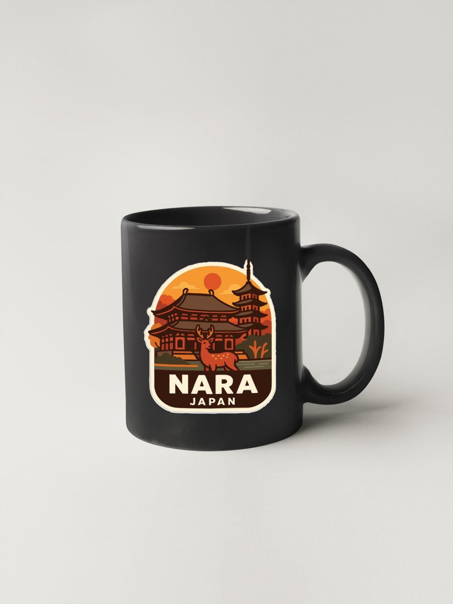 A black coffee mug with a sticker depicting a temple and a sunset in Japan.