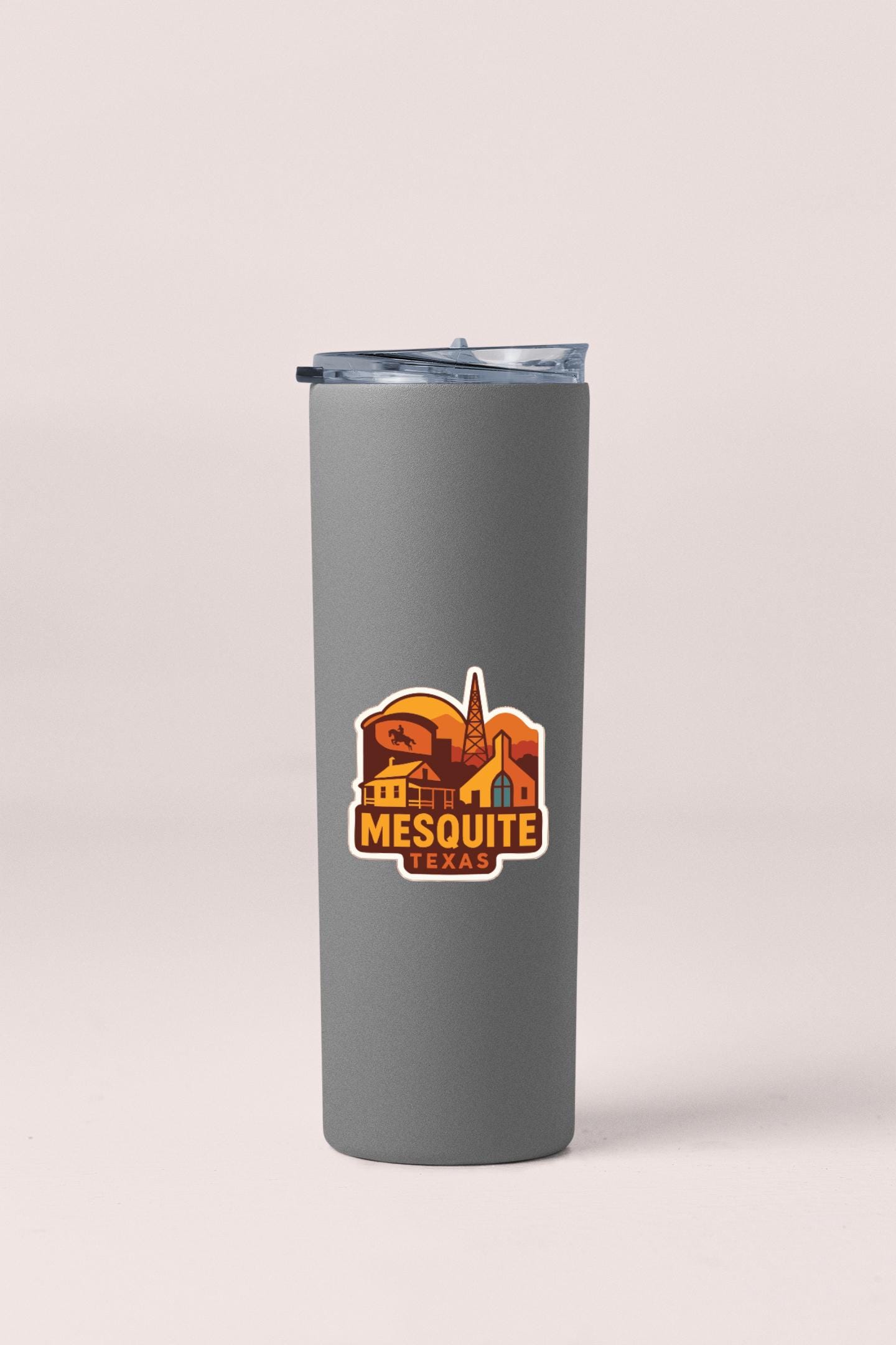 A gray insulated tumbler with a lid and a colorful logo that says "Mesquite, Texas" on it.