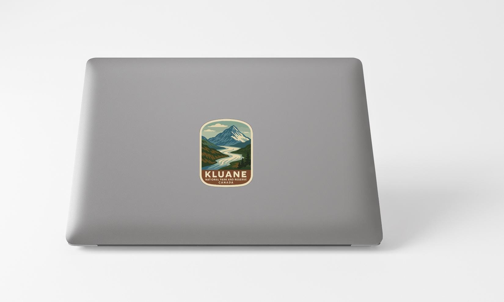 A sticker with a mountain landscape and the text "KLUANE" printed on a laptop.