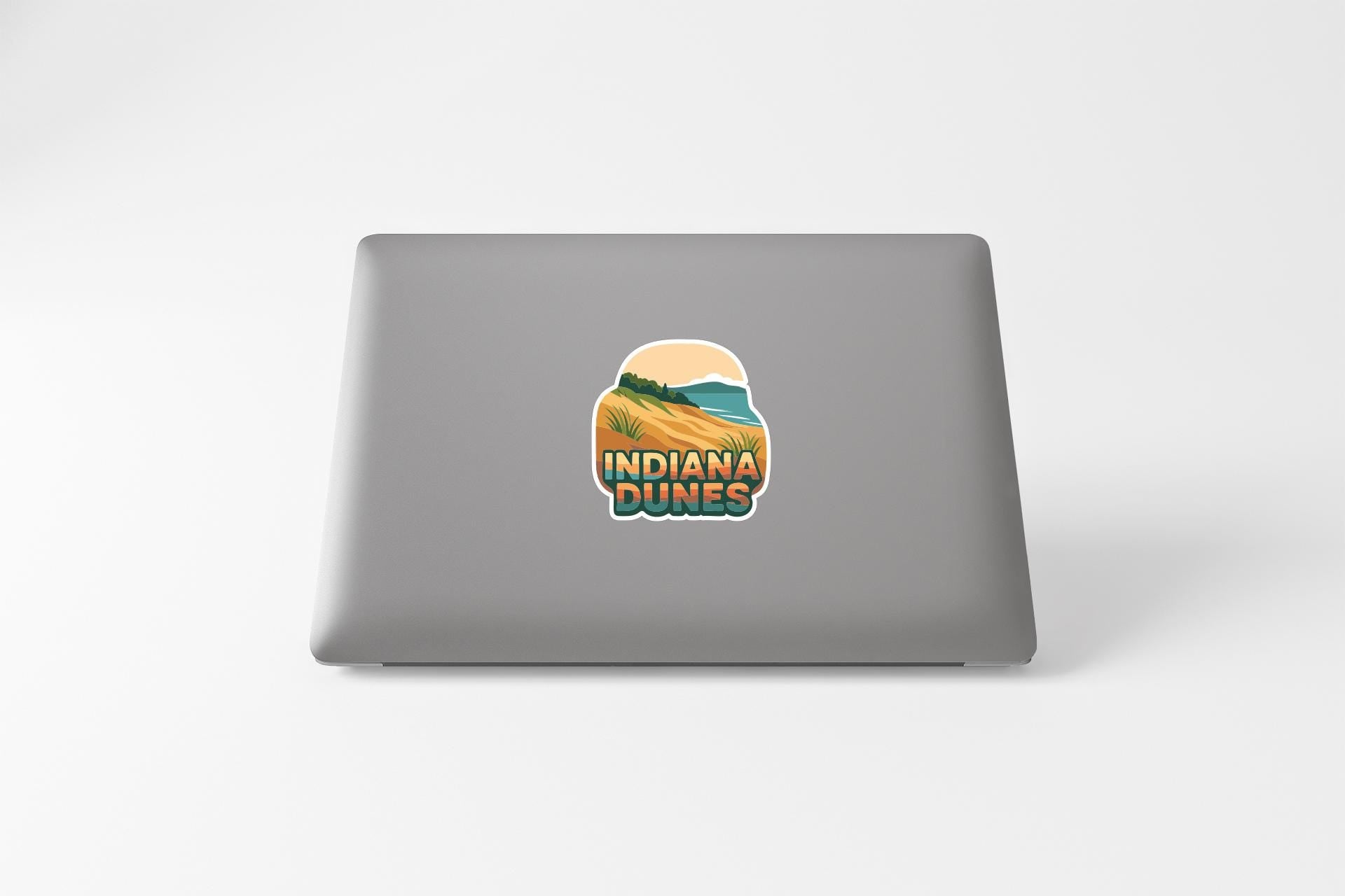 a sticker with the text "Indiana Dunes" on the back of a laptop.