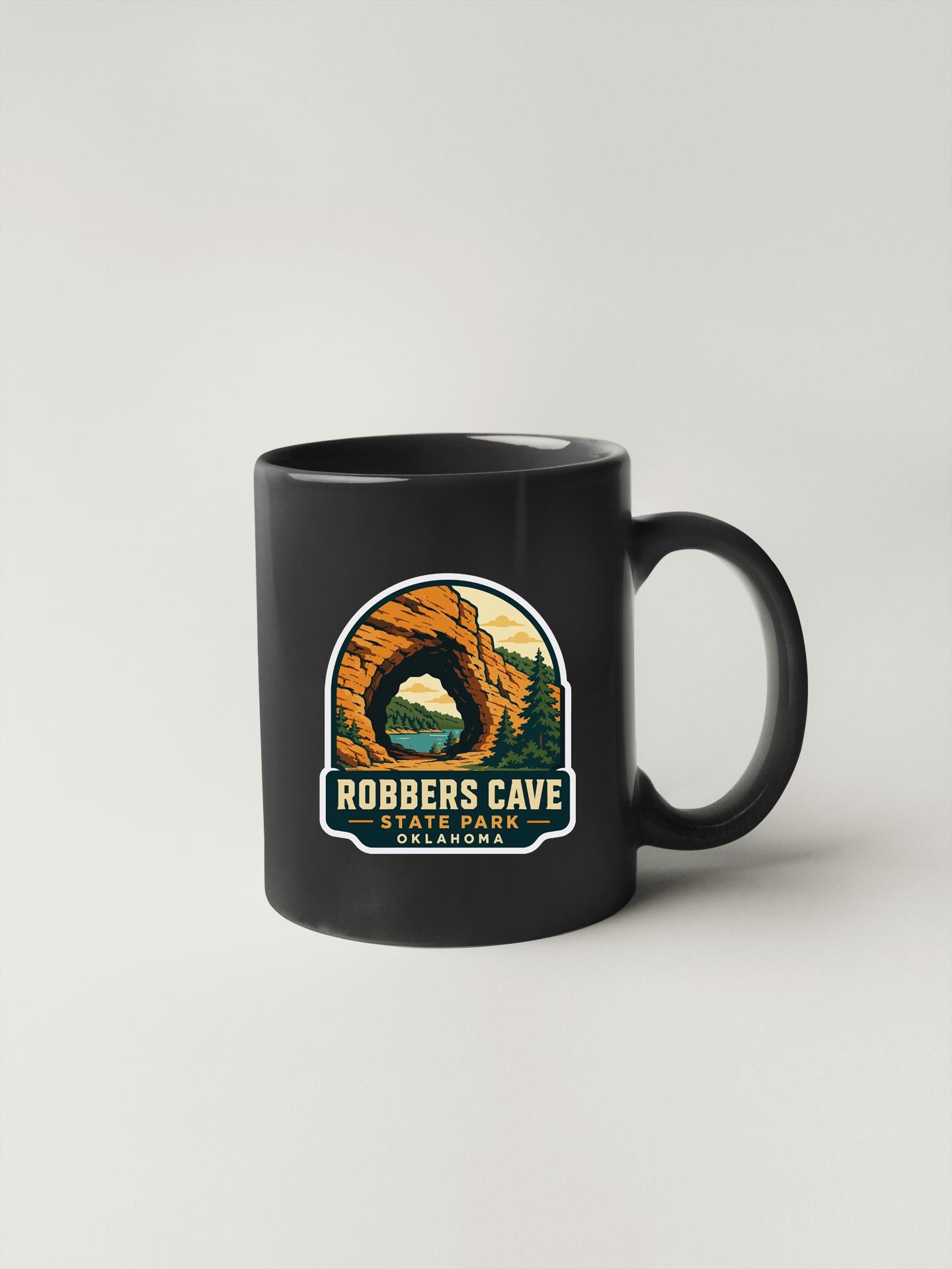 A black coffee mug with a graphic design depicting Robbers Cave State Park in Colorado.