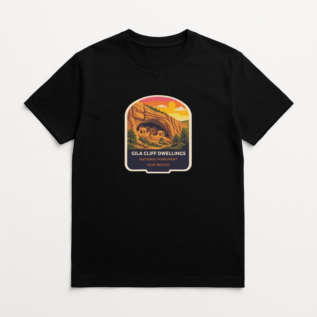 A black t-shirt with a graphic design depicting a desert landscape with a cave or rock formation in the background.