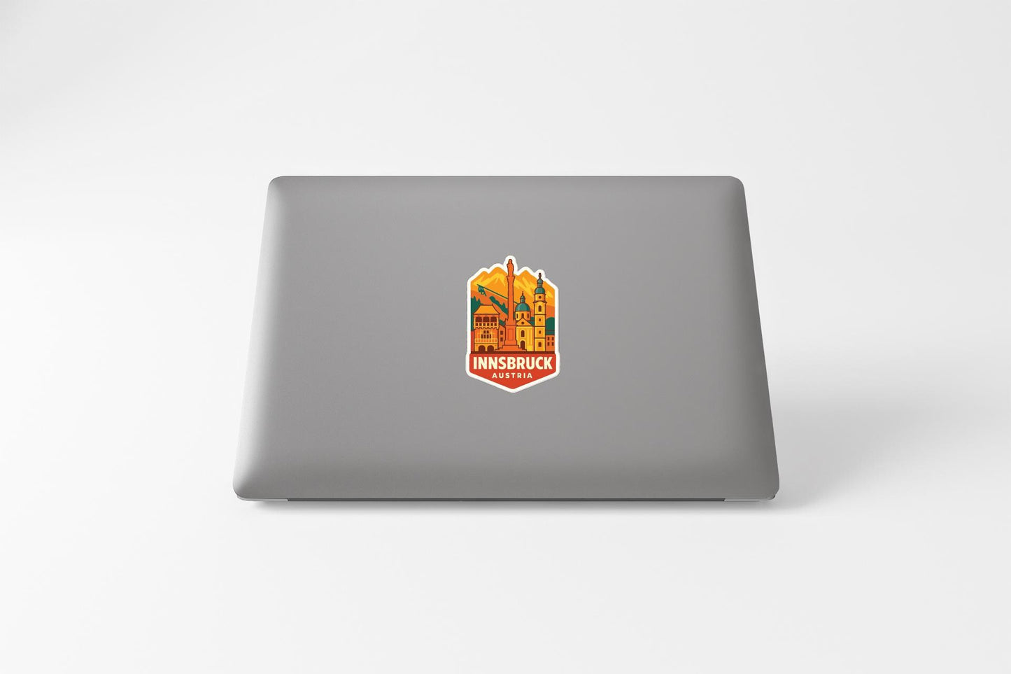 a sticker with a colorful illustration of a cityscape on the back of a laptop.