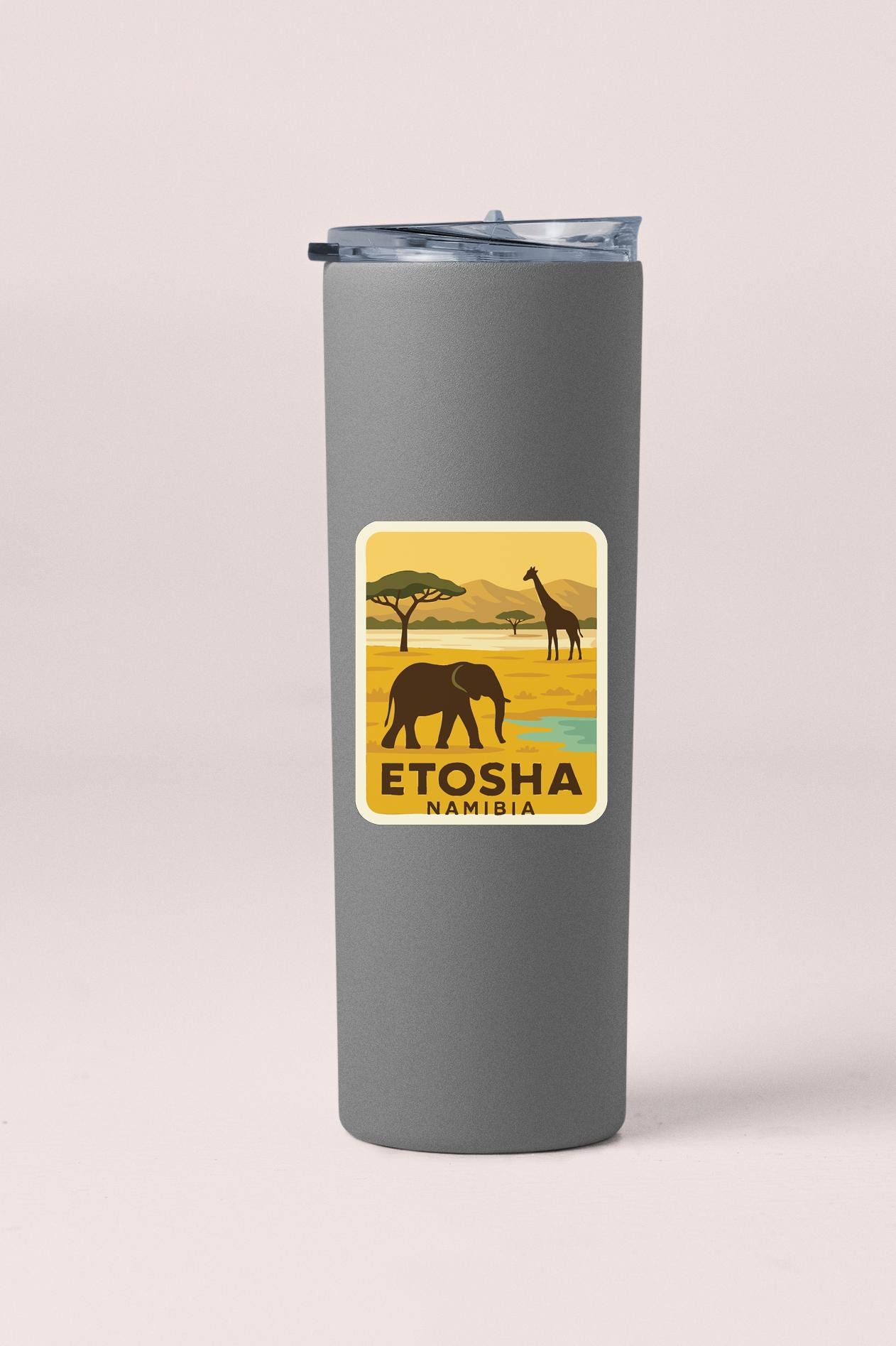A gray tumbler with a label that features an illustration of an elephant and a giraffe in a savanna landscape, along with the text "ETOSHA NAMIBIA".