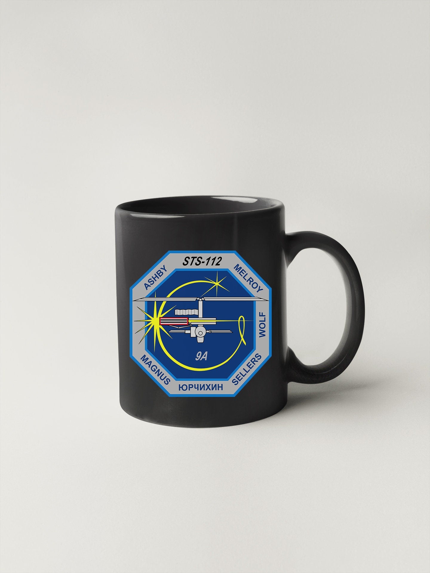 a black coffee mug with a space shuttle on it