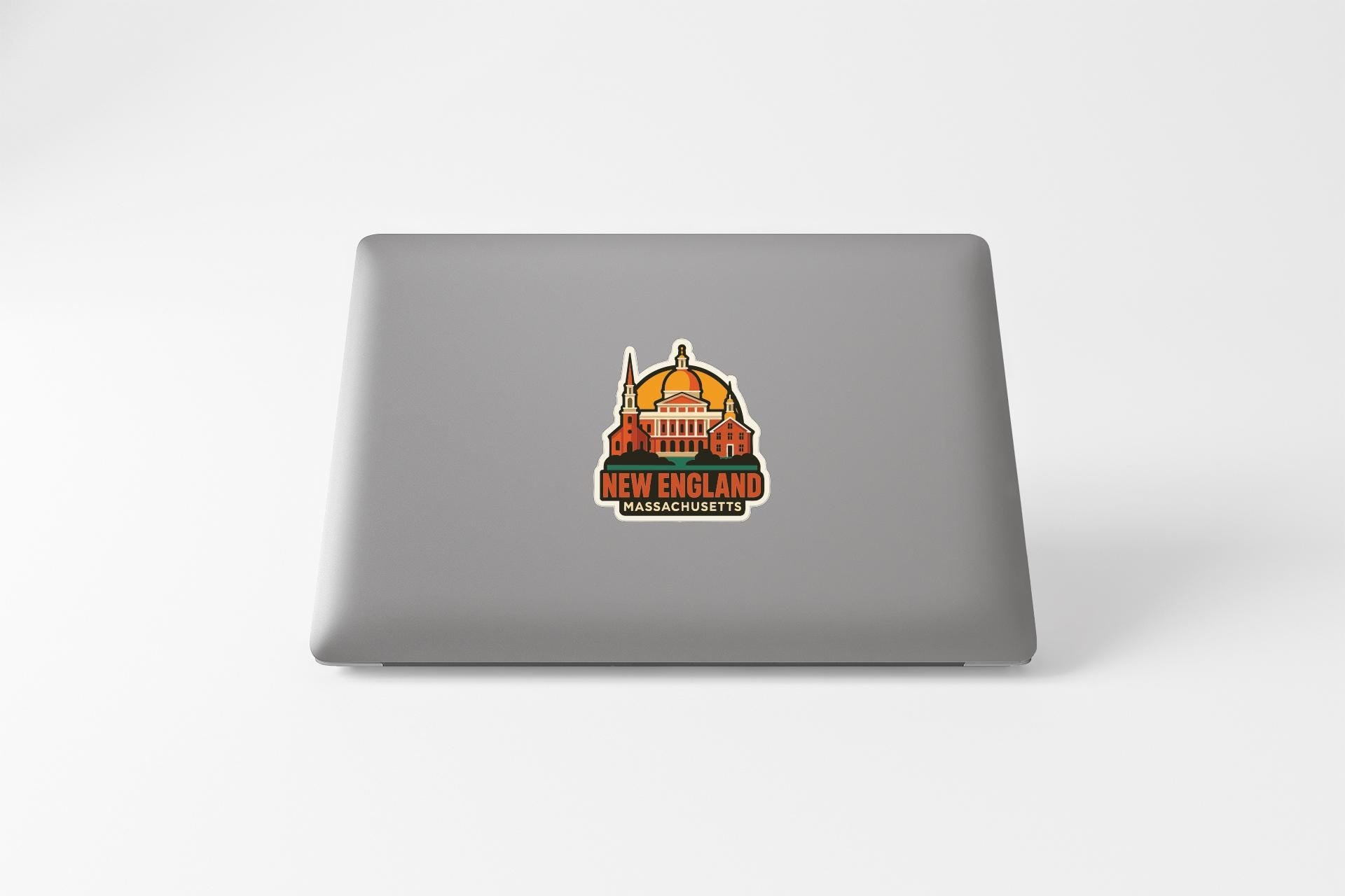 A sticker on the back of a laptop that features an illustration of a building and the text "NEW ENGLAND" and "MAASCHUSETTS".