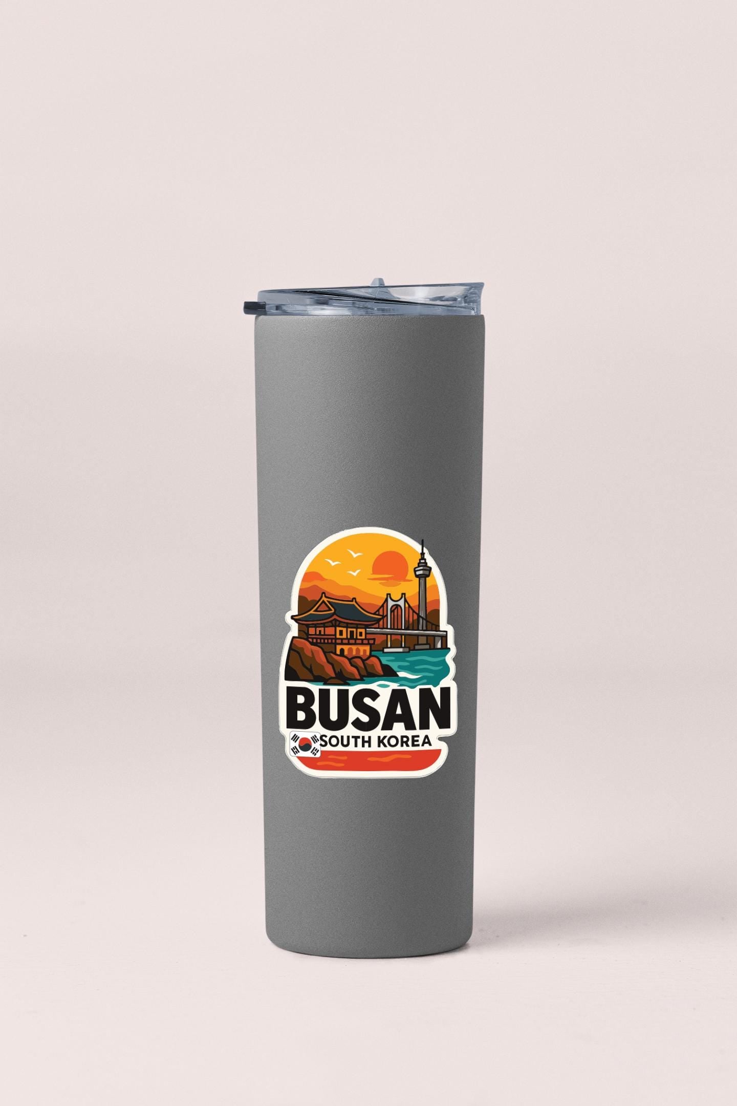 A gray insulated tumbler with a sticker depicting a scenic view of Busan, South Korea.