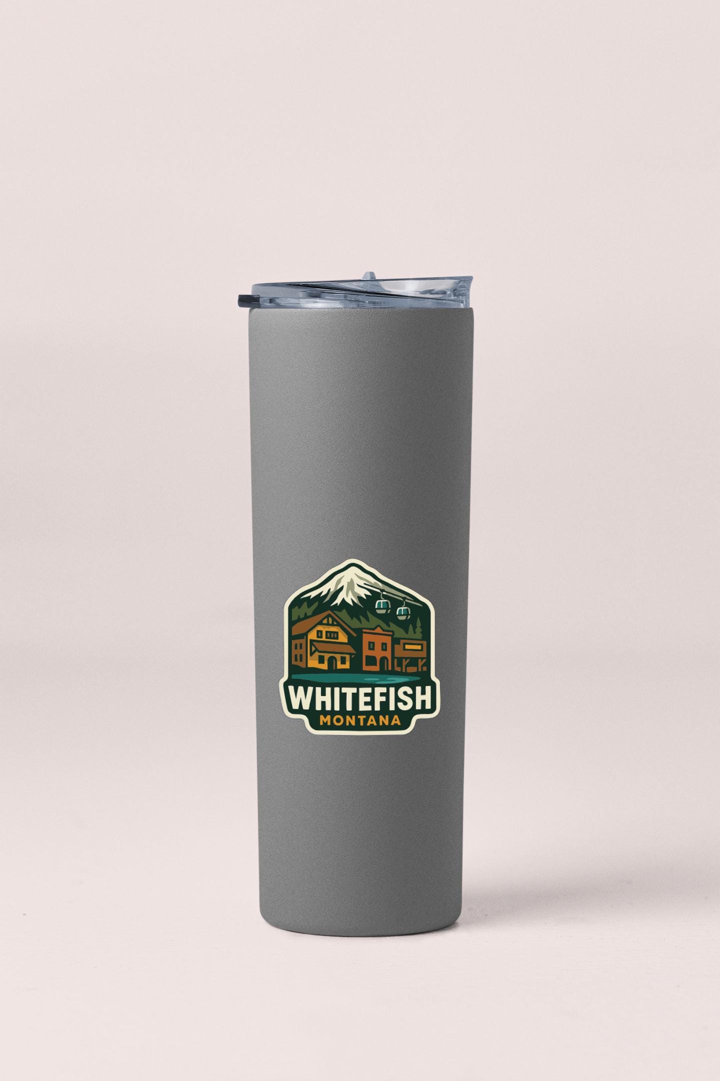 A gray insulated tumbler with a mountain and lodge sticker on it.