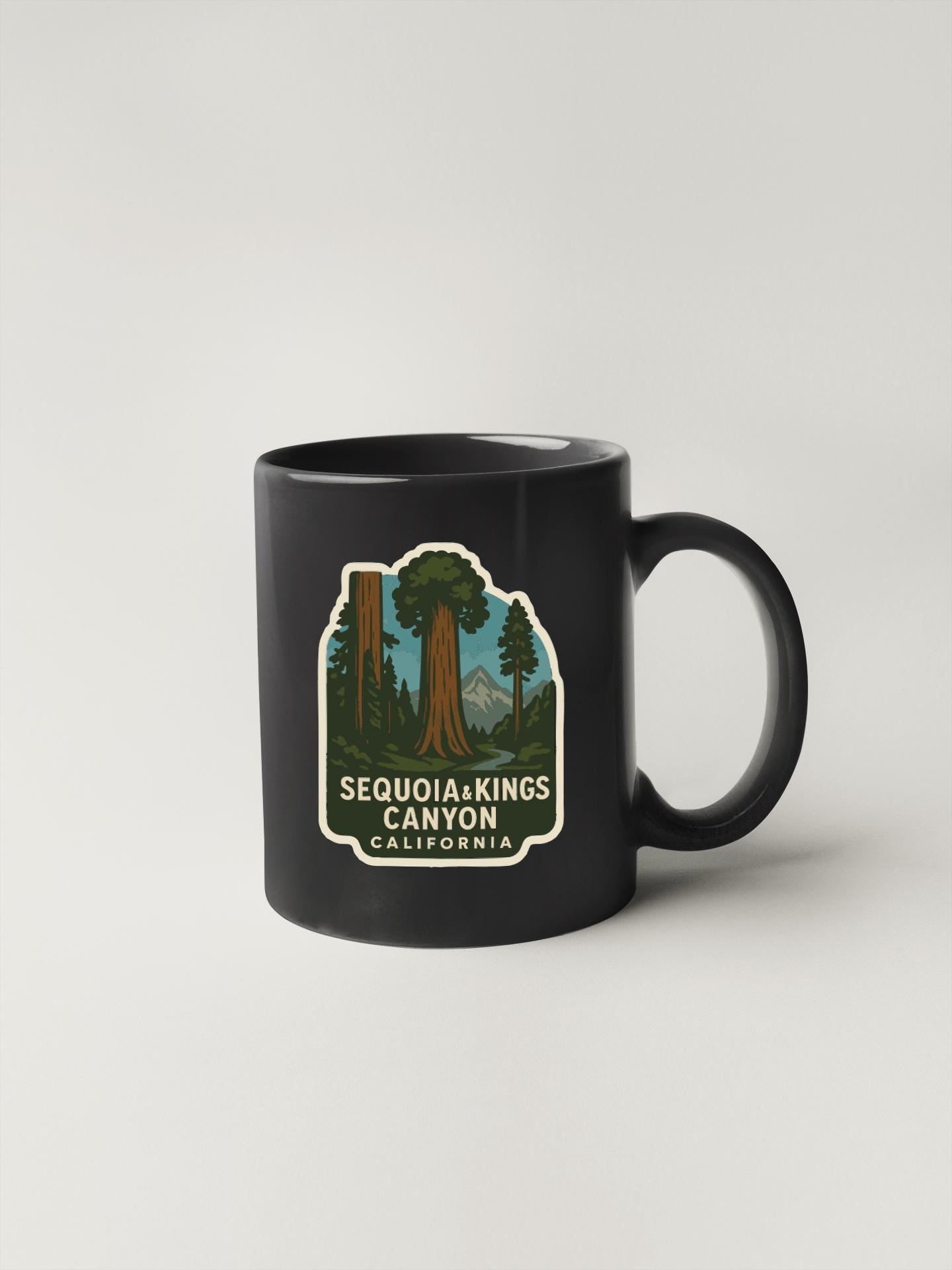 A black coffee mug with a graphic design depicting the Sequoia and Kings Canyon National Parks in California.