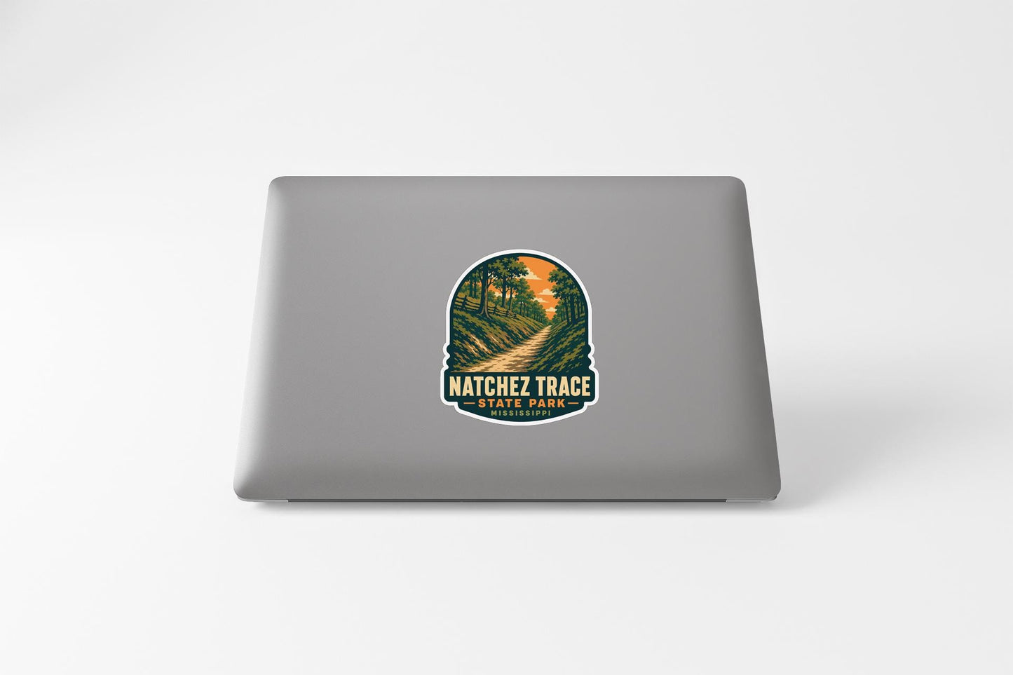 A sticker on the back of a laptop, depicting a scenic landscape with a winding path and trees.