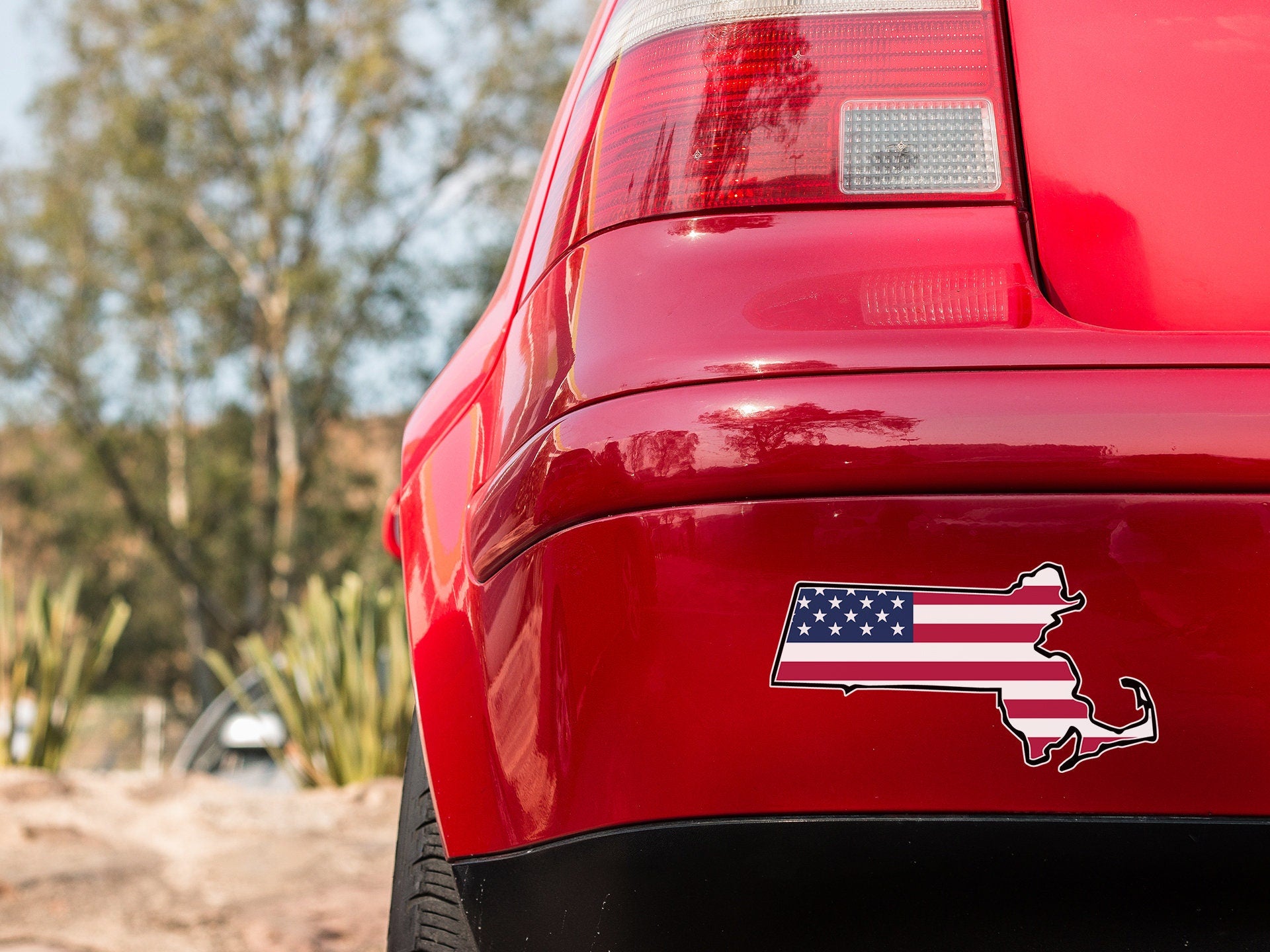 the tail end of a red car with a sticker of the state of texas