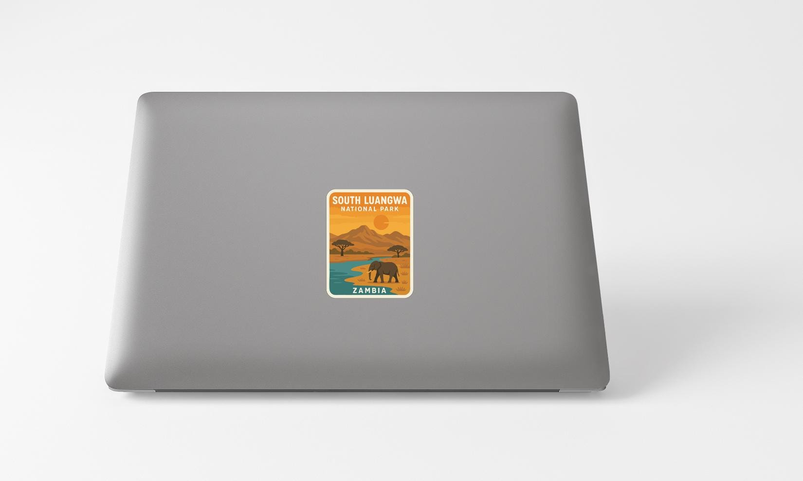 A sticker on the back of a laptop, depicting a scenic landscape with an elephant and mountains in the background.