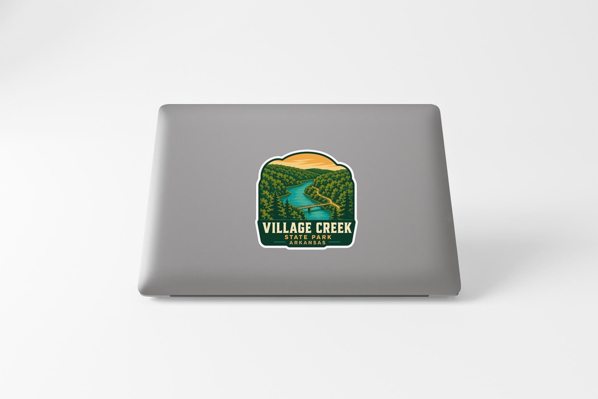 a sticker on a laptop that displays a scenic landscape with a river and forest.