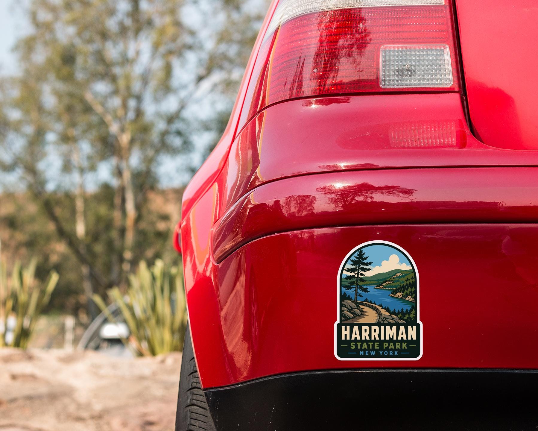 the rear end of a red car with a sticker on the back window that says "HARRIMAN STATE PARK NEW YORK".
