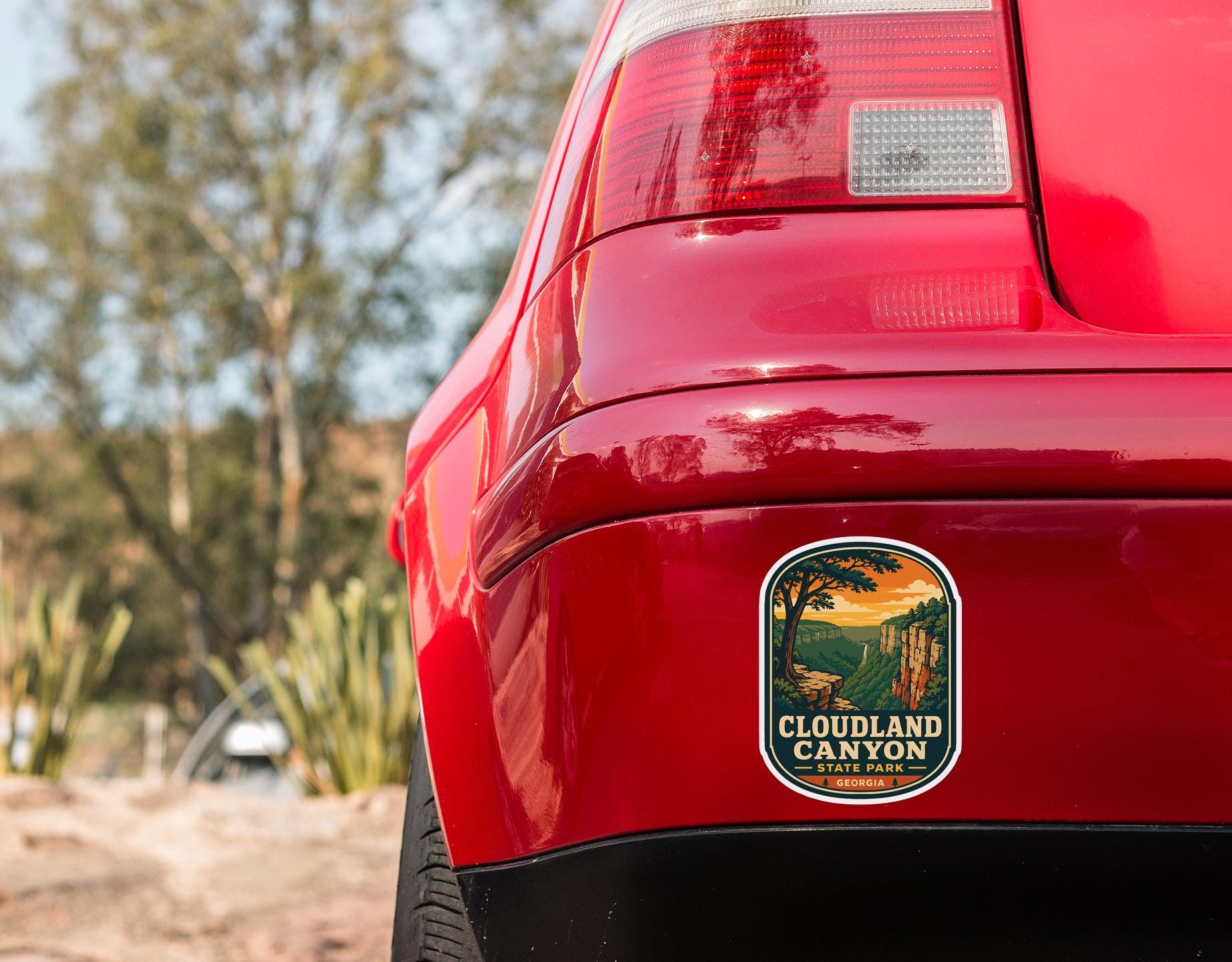 the rear end of a red car with a sticker on the trunk that says "Cloudland Canyon".