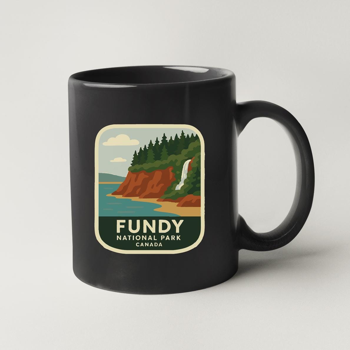 A black coffee mug with a label that says "FUNDY NATIONAL PARK CANADA".