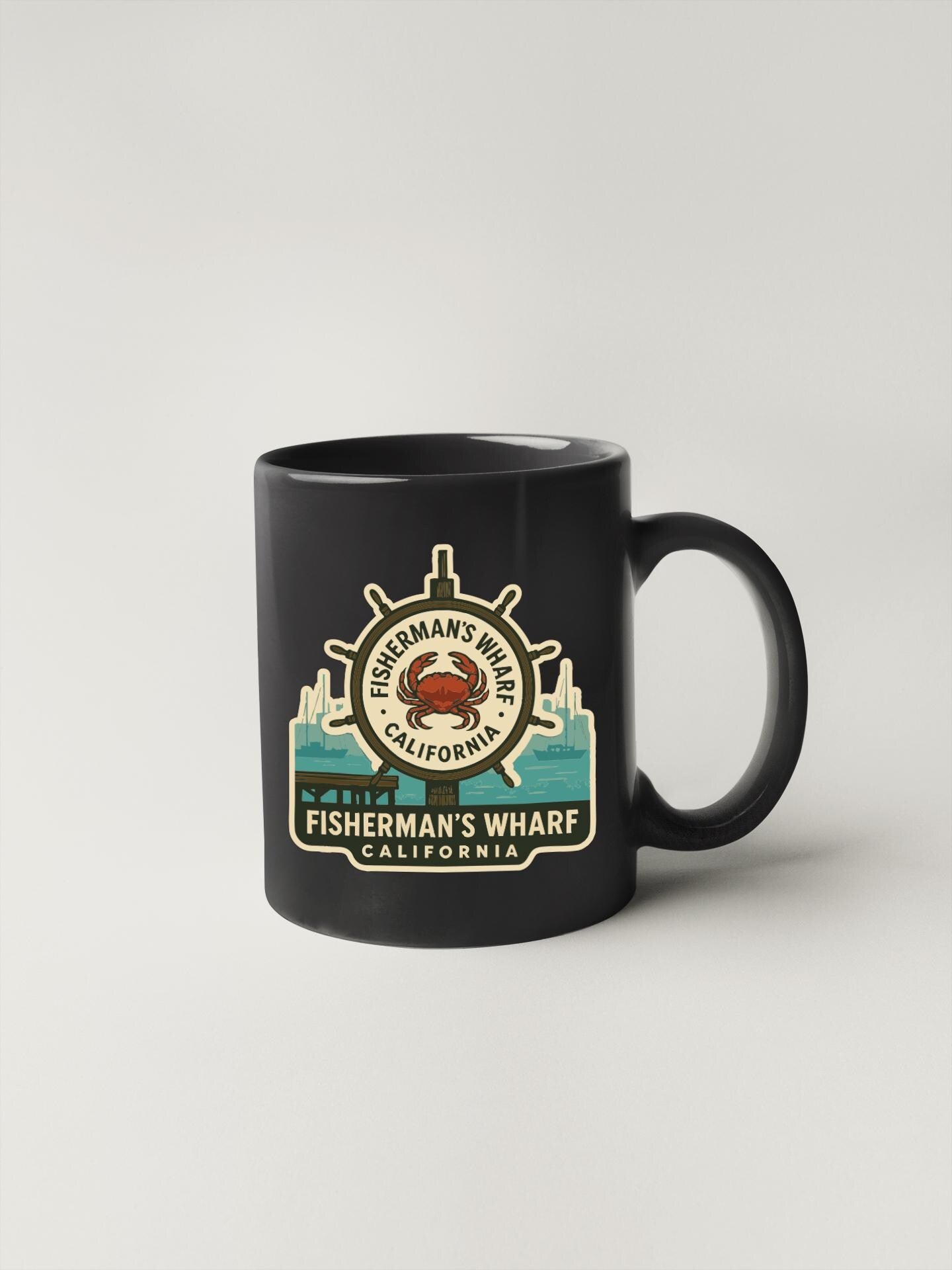 A black coffee mug with a graphic design featuring a ship's wheel and the text "FISHERMAN'S WHARF CALIFORNIA" printed on it.