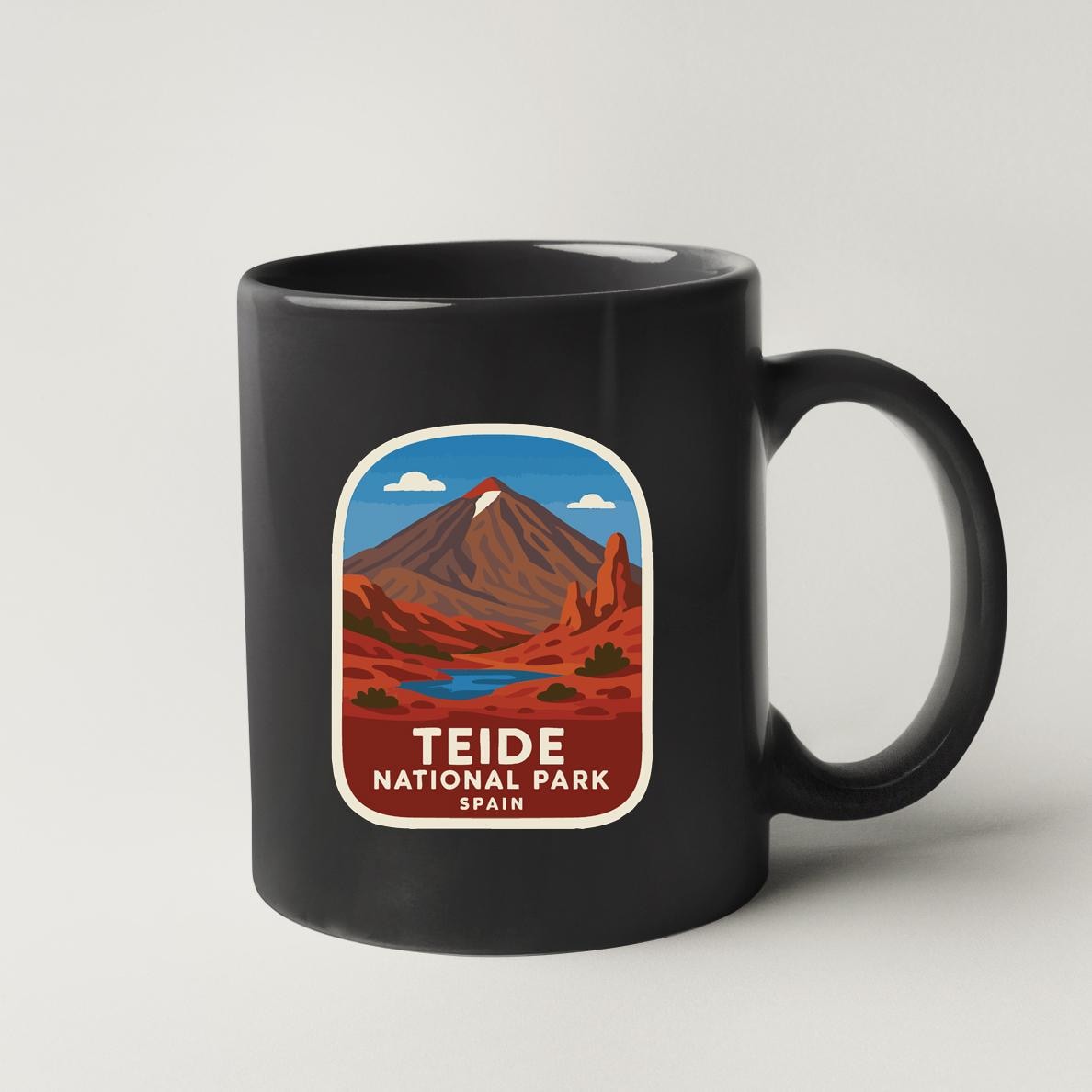 A black coffee mug with a graphic design depicting a mountain landscape and a lake, representing the Teide National Park in Spain.
