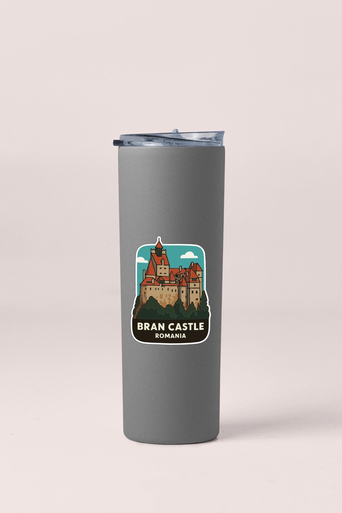A gray insulated tumbler with a sticker depicting the Bran Castle in Romania.
