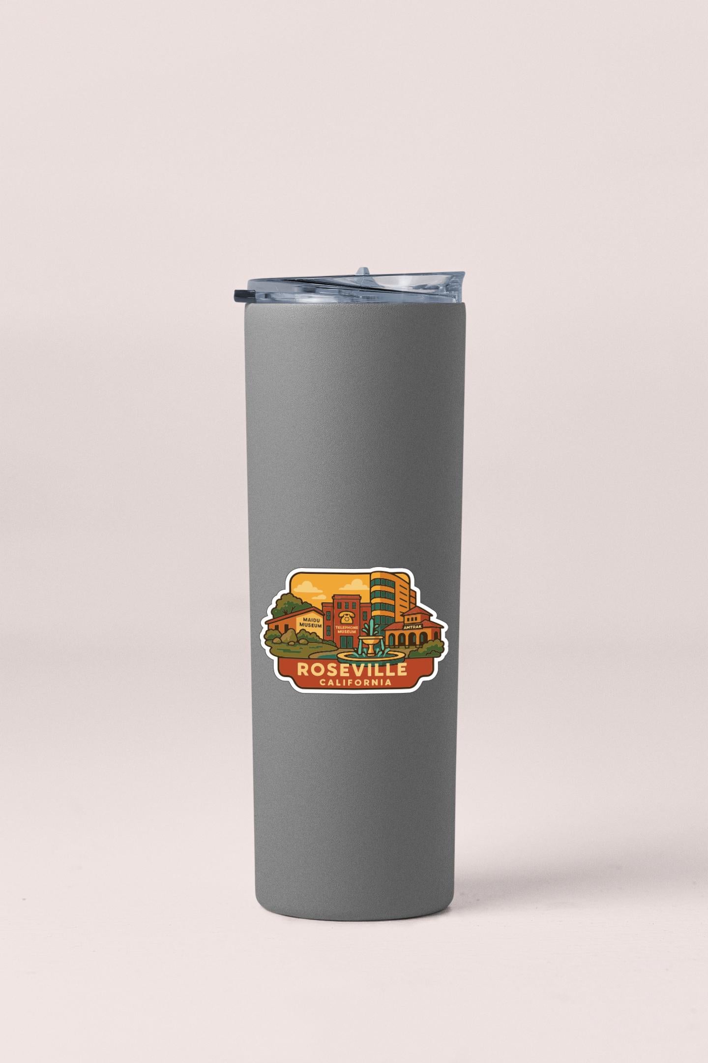 A gray insulated tumbler with a sticker depicting a cityscape.