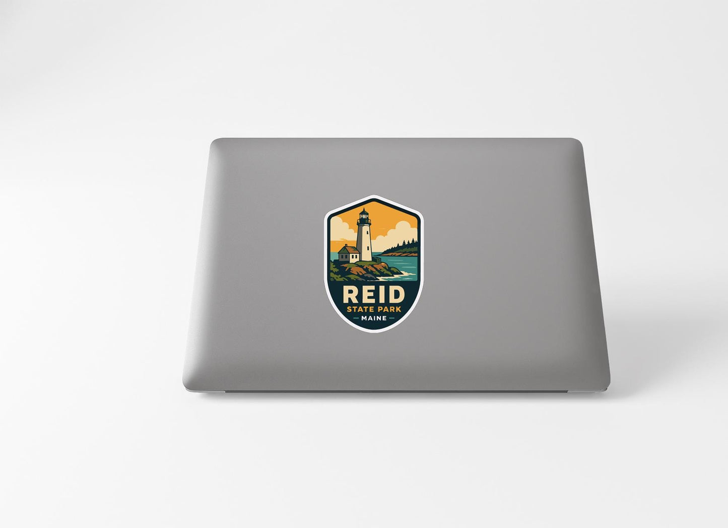 a sticker with a lighthouse and the text "REID STATE PARK" on a laptop.
