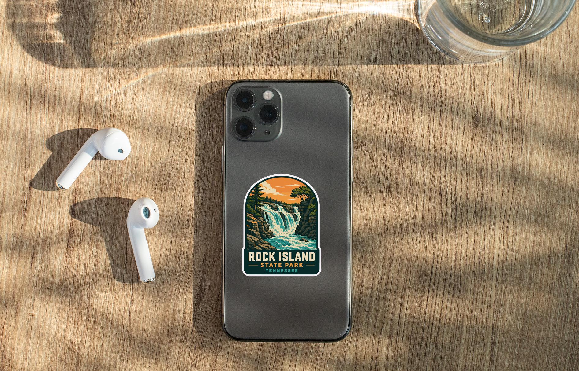 a smartphone with a sticker on it, placed on a wooden surface alongside a pair of white earbuds and a glass of water.