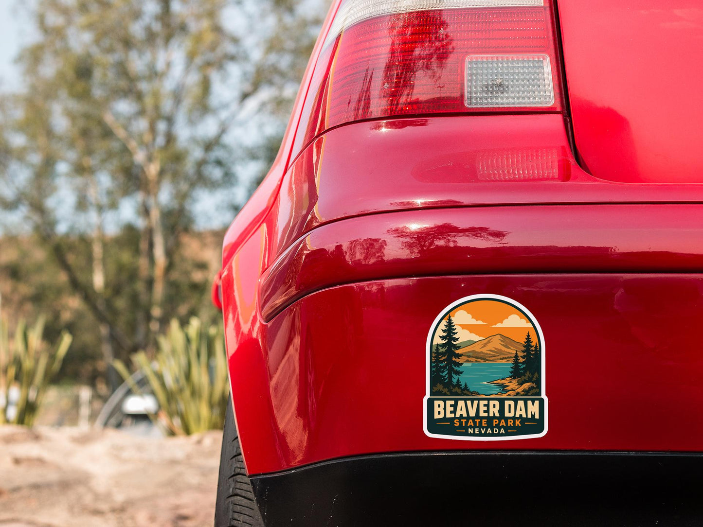 the rear end of a red car with a sticker on the bumper that says "BEAVER DAM STATE PARK NEVADA".