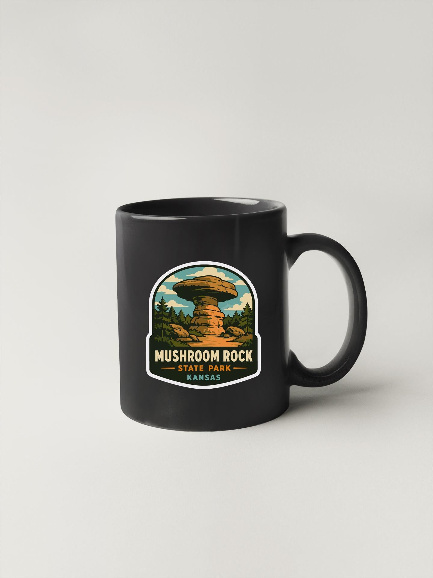 A black coffee mug with a mushroom rock sticker printed on it, depicting a scenic landscape.