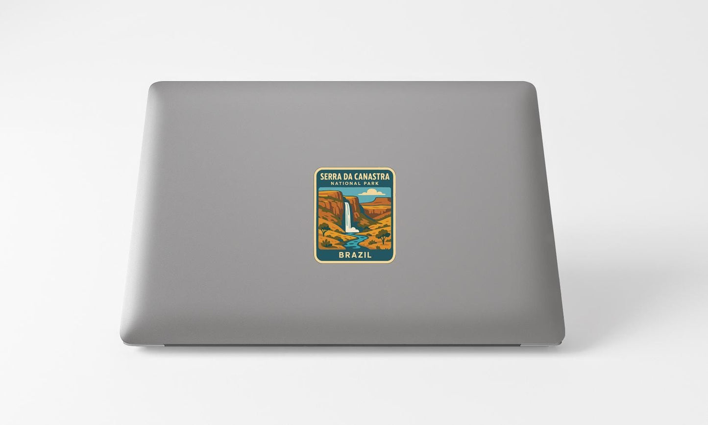A sticker on the back of a laptop, depicting a scenic landscape with a waterfall and mountains.