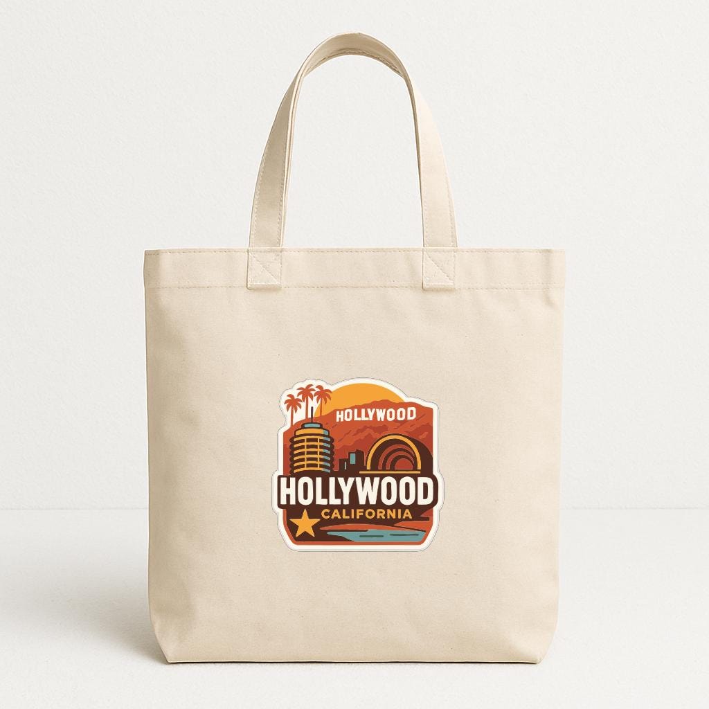 A beige tote bag with a graphic design featuring the text "Hollywood California" and a stylized illustration of a city skyline.