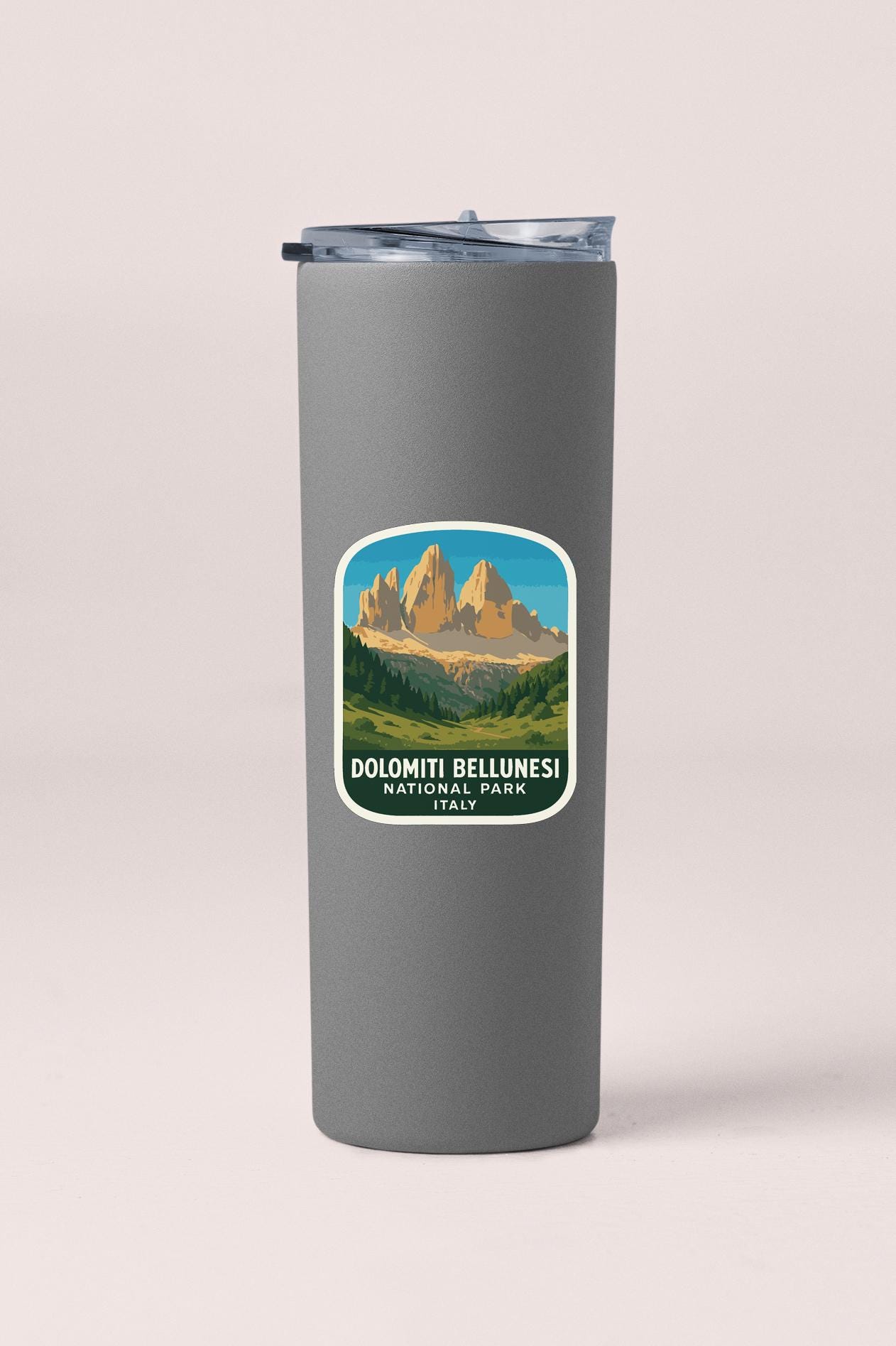 A gray insulated tumbler with a sticker depicting Dolomiti Bellunes, a famous mountain range in Italy.