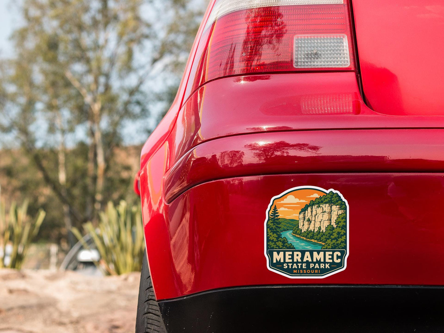 the rear end of a red car with a sticker on the back window that says "MERAMEc State Park, Missouri".