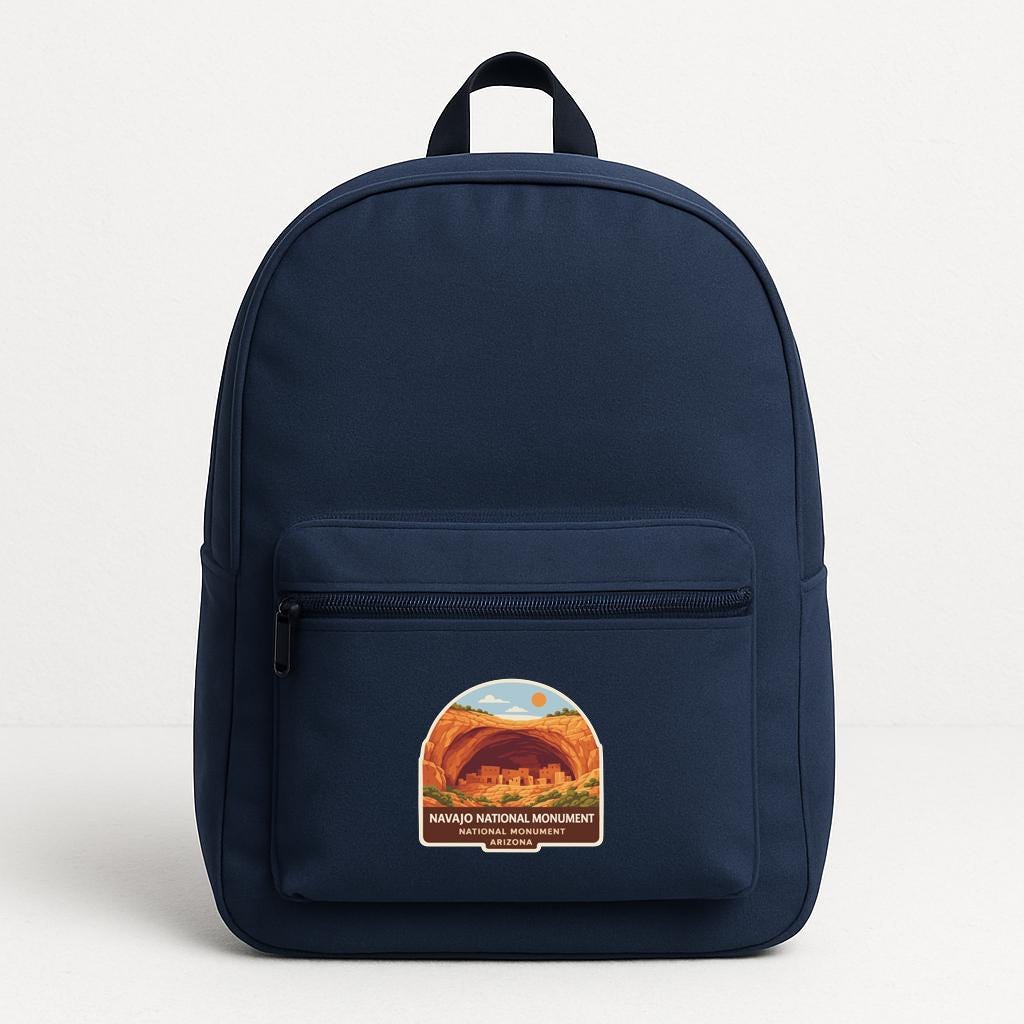 A navy blue backpack with a sticker on the front that says "NAVAGO NATIONAL MONUMENT ARIZONA".