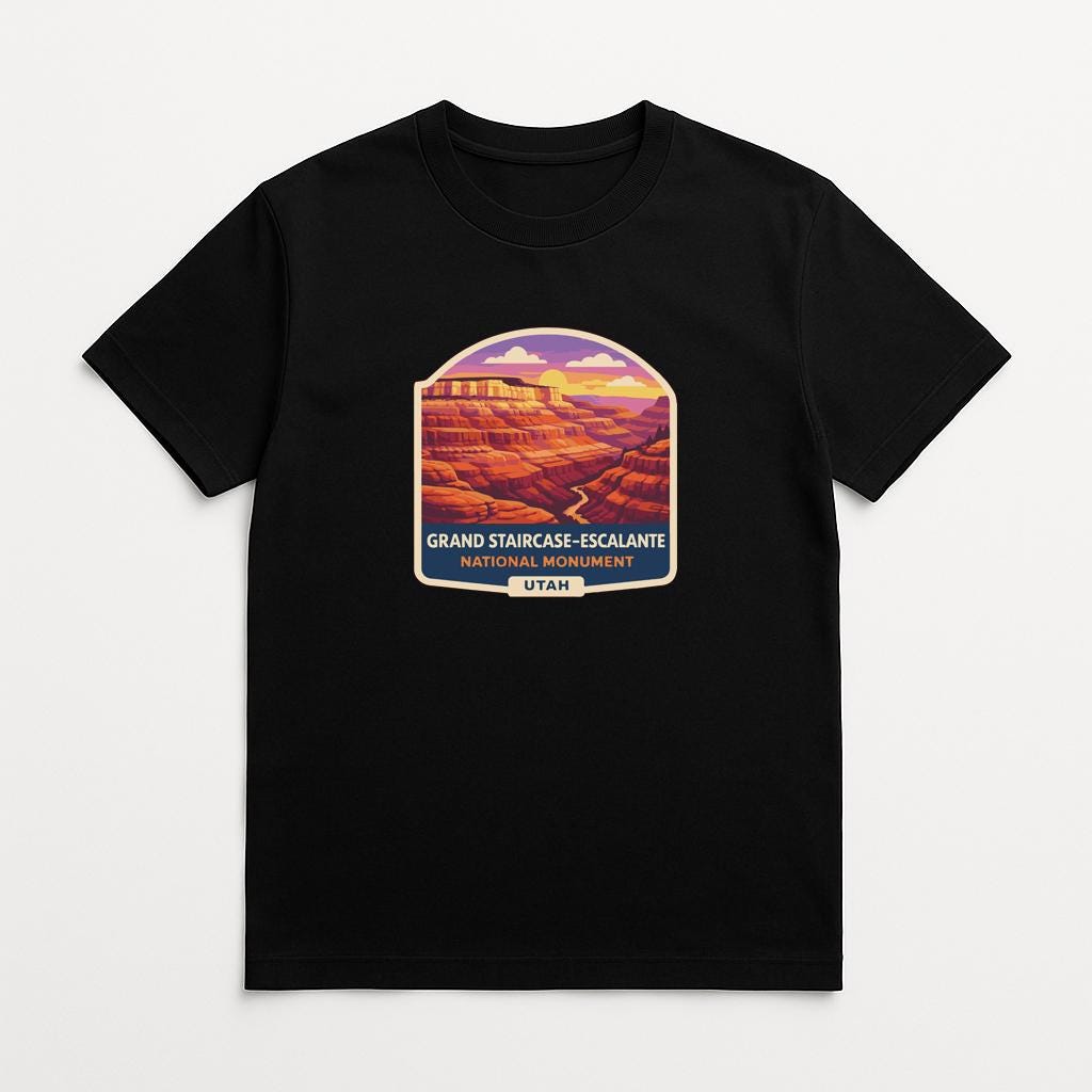 A black t-shirt with a graphic design depicting the Grand Staircase-Escalante National Monument in Utah.