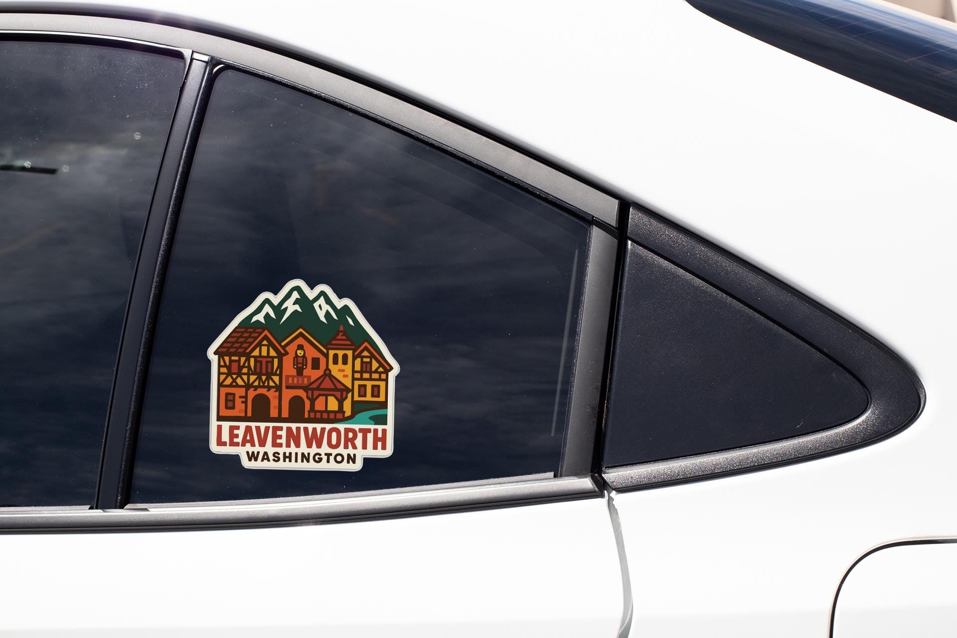 A sticker on the side of a car window, depicting a house with mountains in the background.