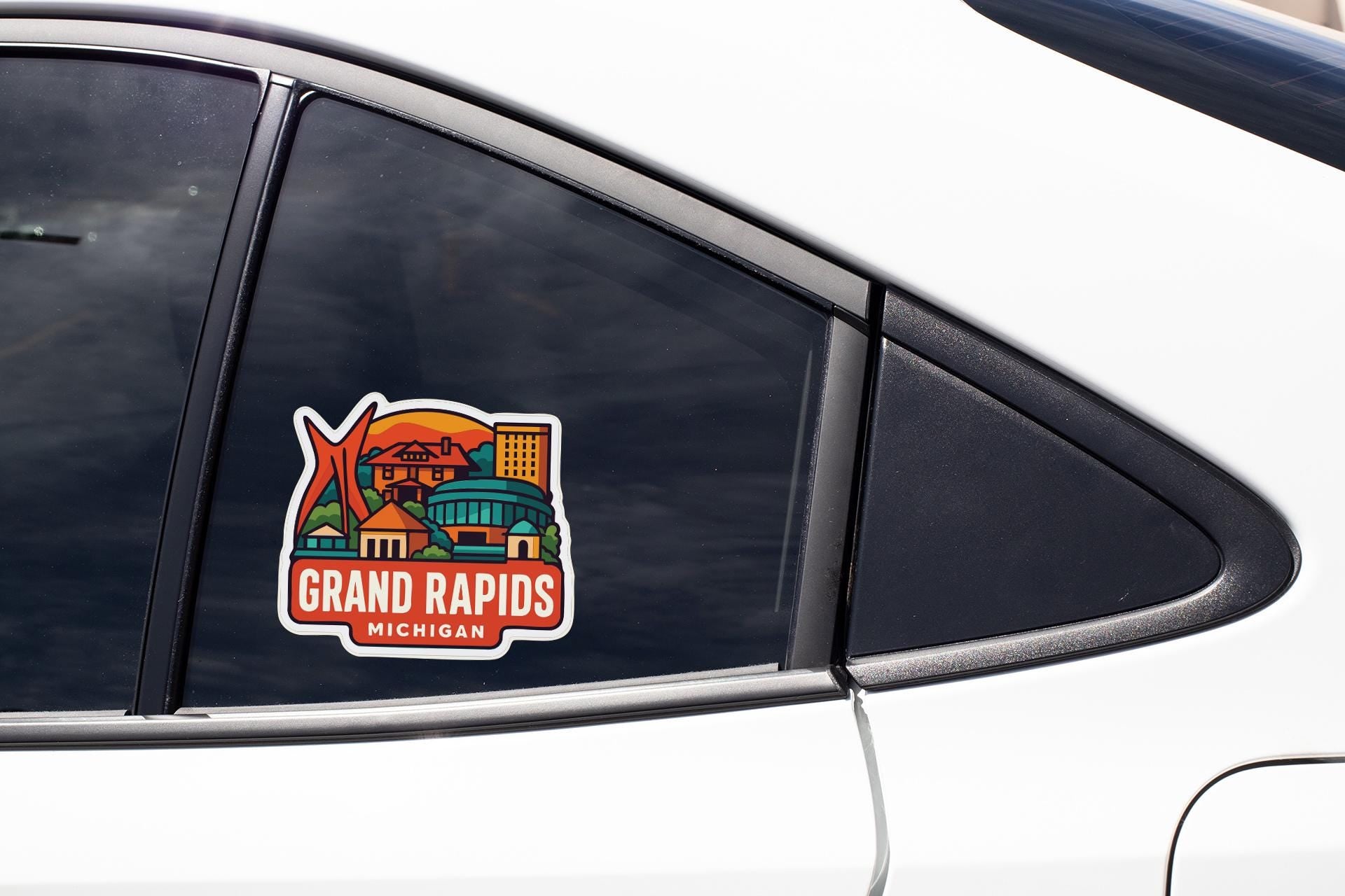 A car window sticker with a colorful illustration of a city skyline and the text "GRAND RAPIDS MICHIGAN".