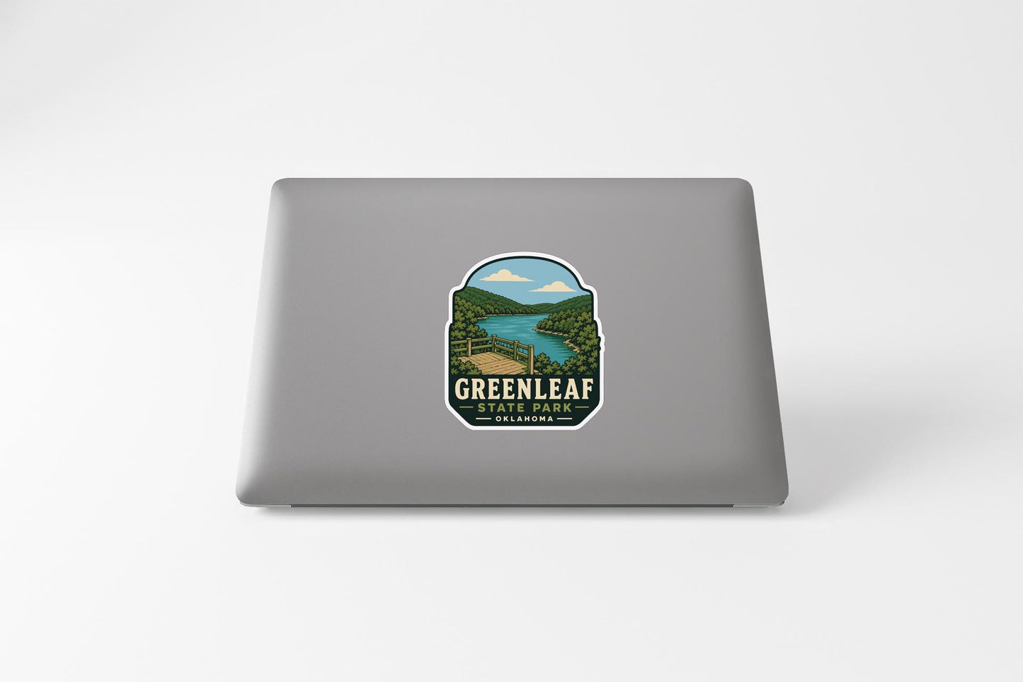 A sticker on the back of a laptop that features a scenic landscape with a river and mountains, along with the text "GREENLEAF STATE PARK".