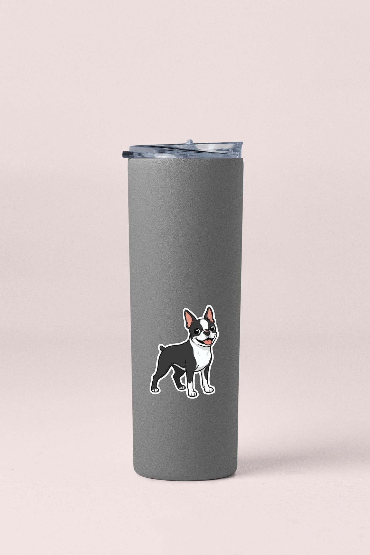 A gray insulated tumbler with a sticker of a dog on it.