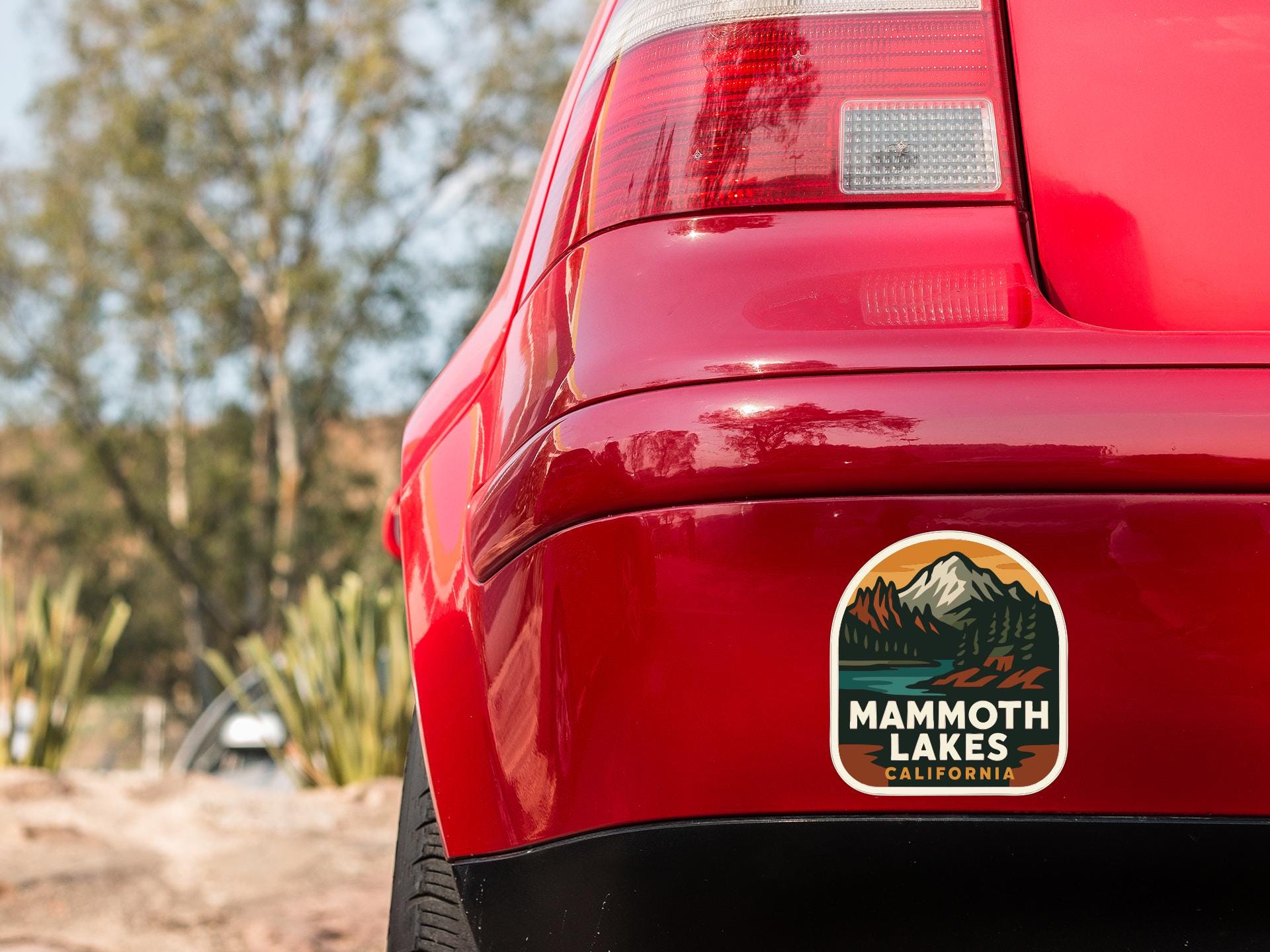 the rear end of a red car with a sticker on the trunk that says "Mammoth Lakes California".