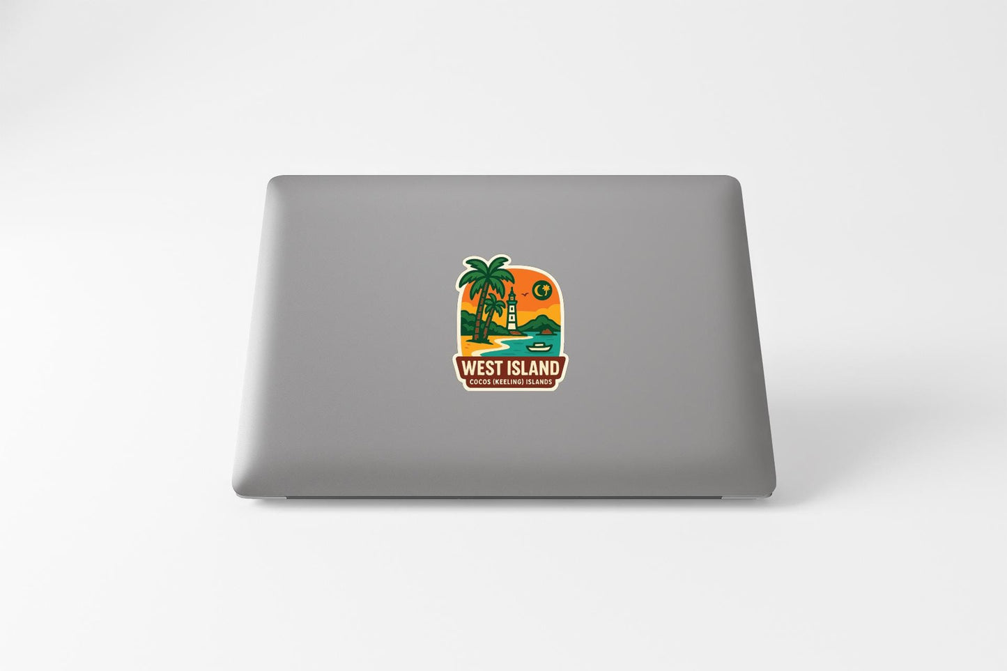 A sticker on the back of a laptop, depicting a tropical island scene with palm trees, a sunset, and a house.