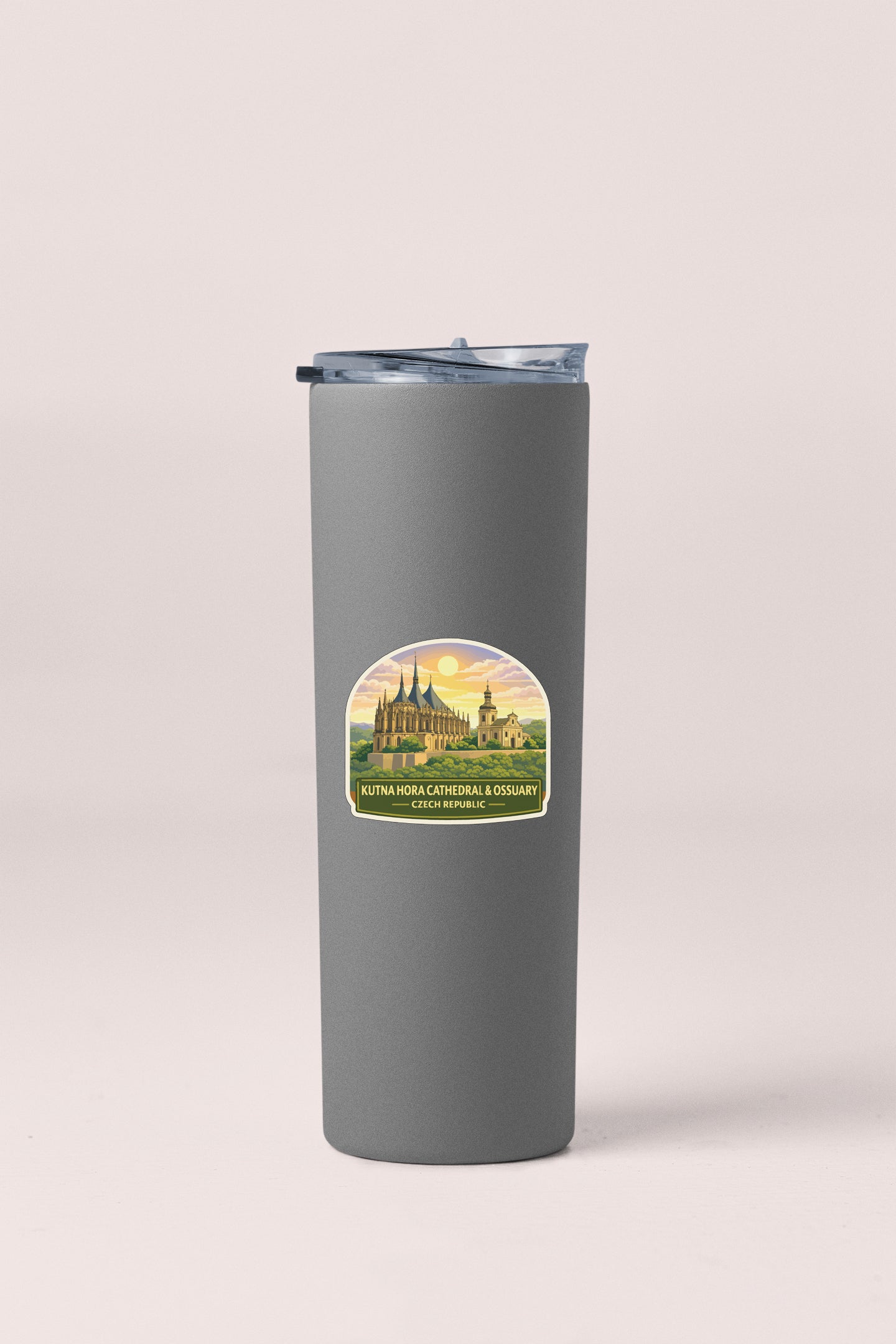 A gray insulated tumbler with a label depicting a cathedral and a sunset.