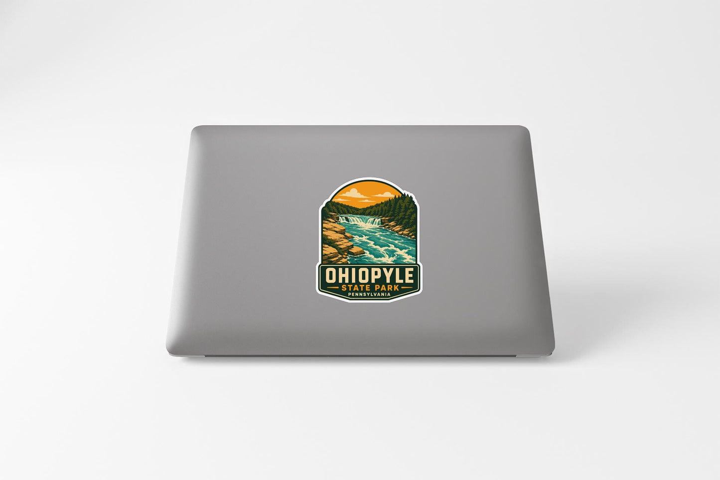 A sticker on the back of a laptop, depicting a scenic landscape with a river and mountains.