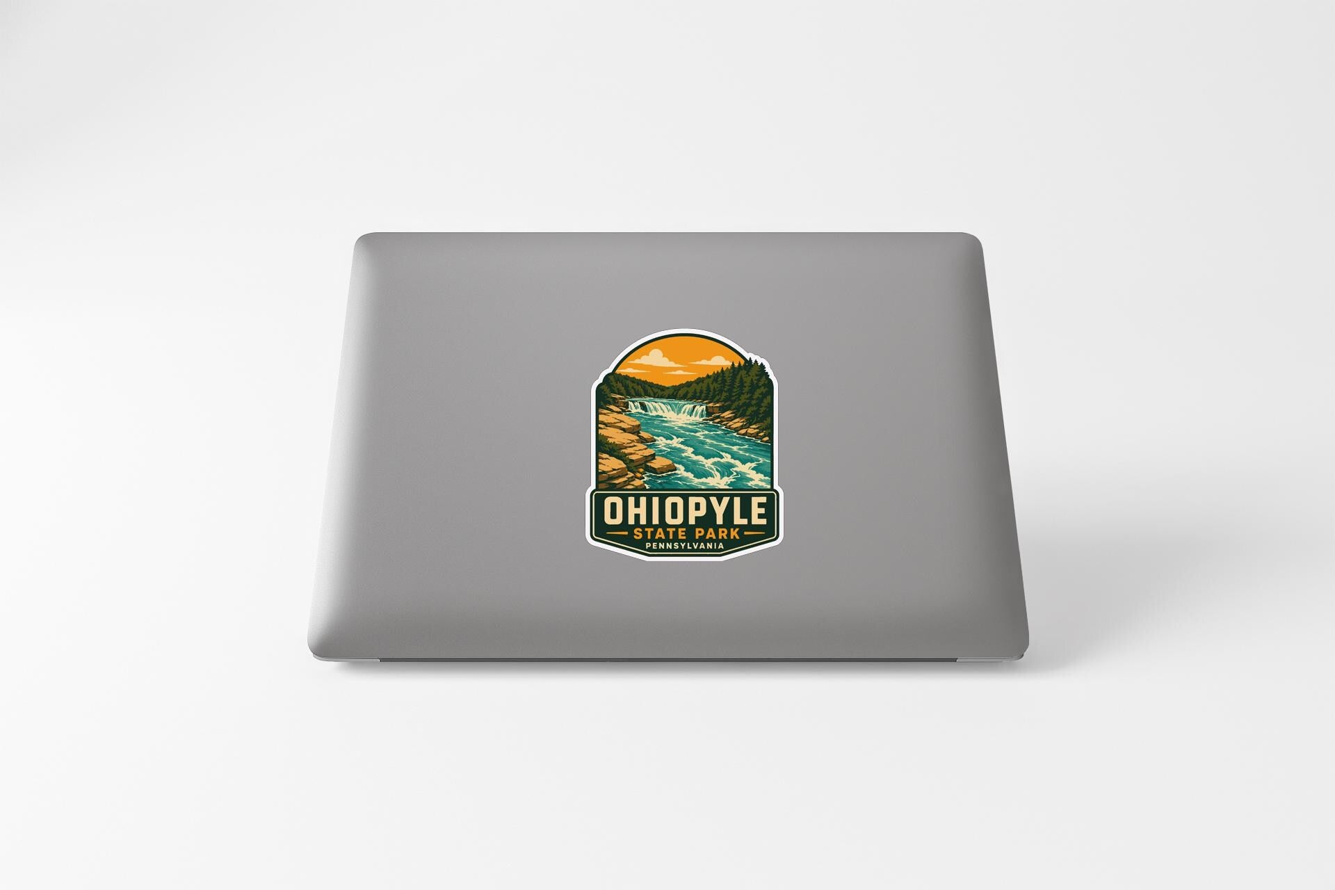 A sticker on the back of a laptop, depicting a scenic landscape with a river and mountains.