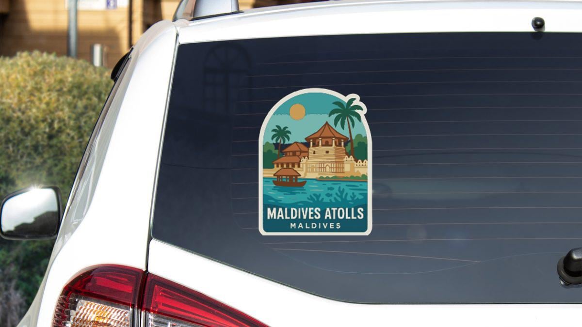 A sticker on the rear window of a car, depicting a tropical island with palm trees and a building, along with the text "Maldives Atolls Maldives".