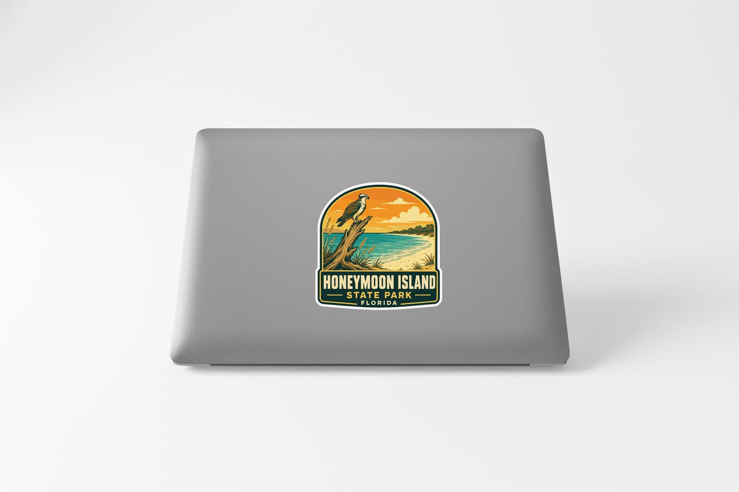 A sticker on the back of a laptop, depicting a scenic landscape with a bird and a sunset.