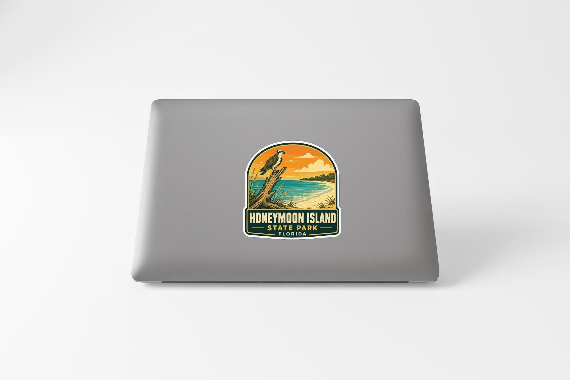 A sticker on the back of a laptop, depicting a scenic landscape with a bird and a sunset.
