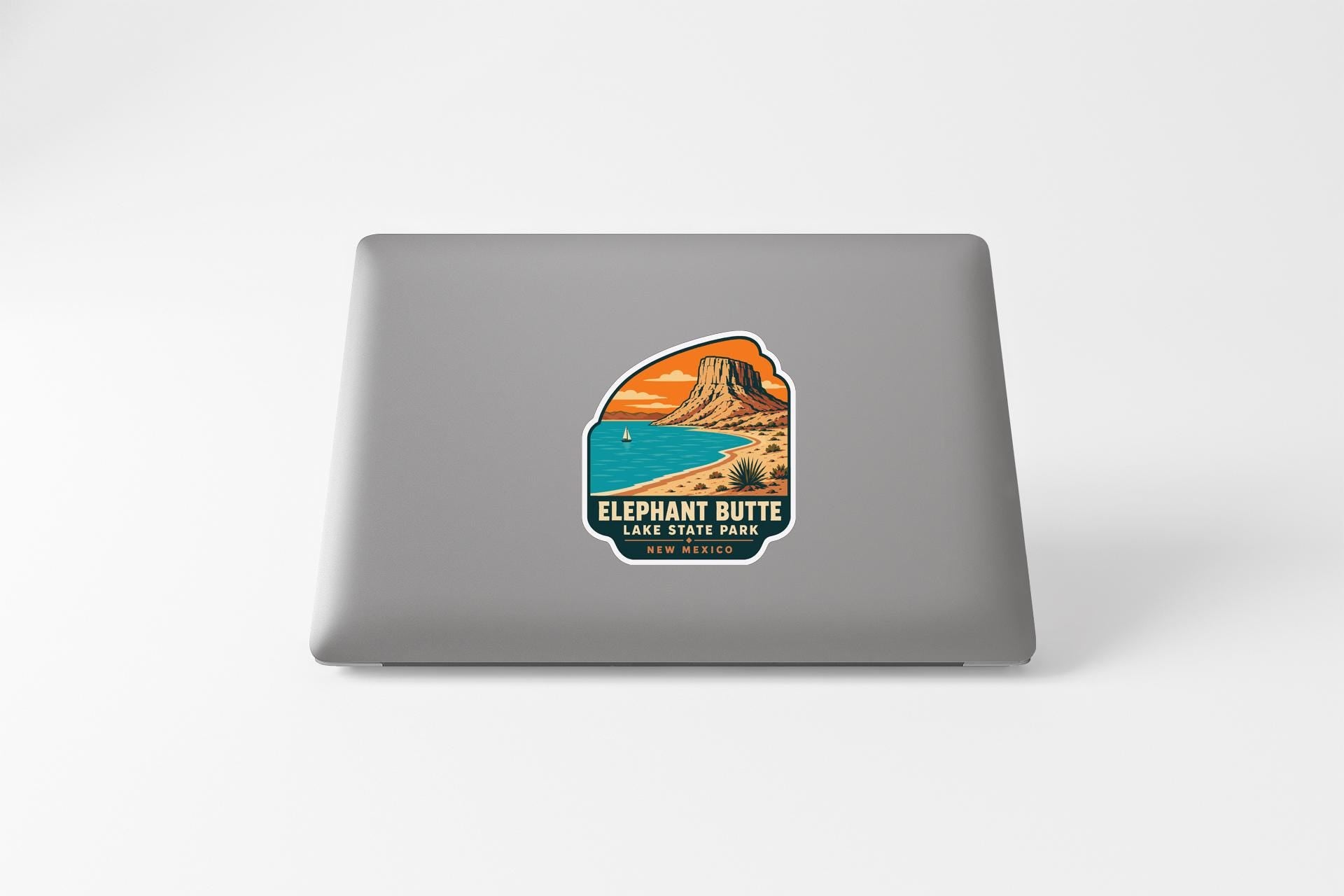 a sticker on a laptop that depicts a mountain landscape with a beach and a sailboat in the background.